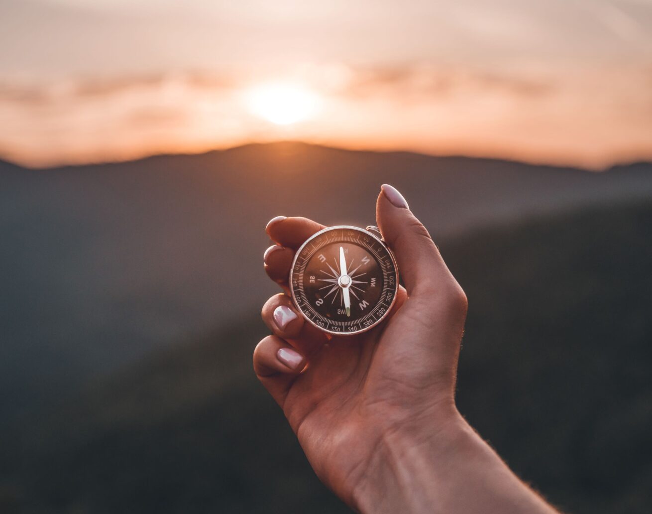 Compass in a hand at sunset